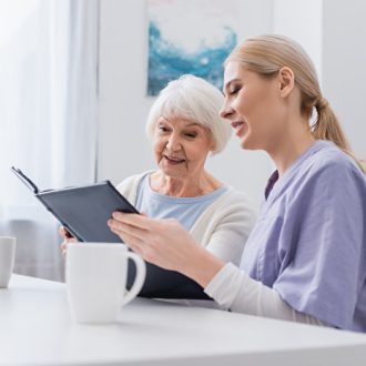 Betreuerin mit alter Dame und Fotoalbum